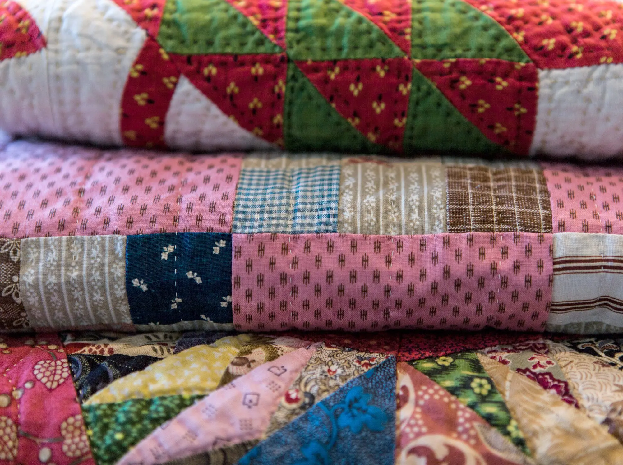 A close up of three different colored quilts