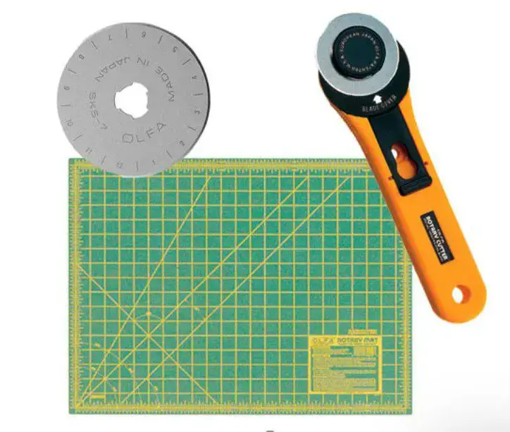 A cutting mat, rotary cutter and blade are all on the table.