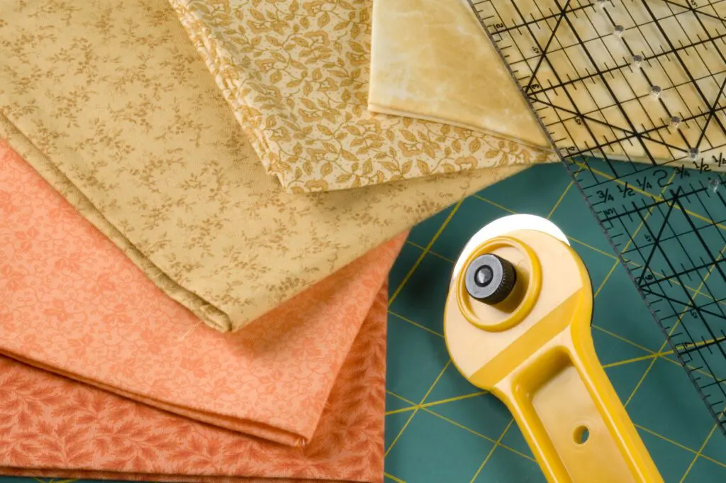 A yellow rotary cutter and some fabric on top of a table.