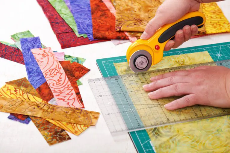 A person using a rotary cutter to cut fabric.