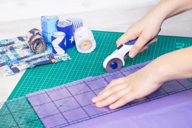 A person using a rotary cutter on a purple mat.